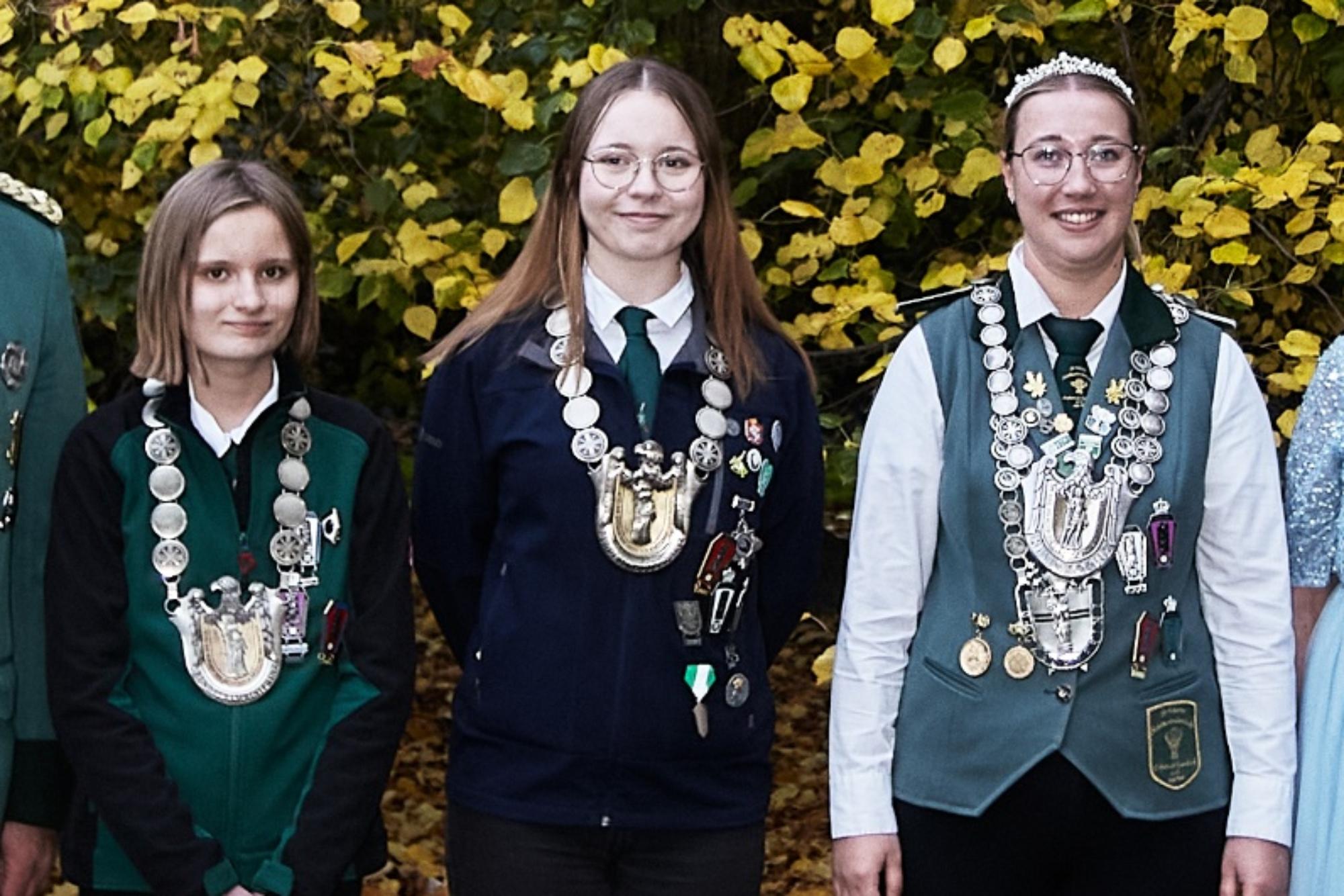 Zu sehen sind die drei neuen Bundesprinzessinen mit ihren Ketten, fotografiert vor einem Gebüsch