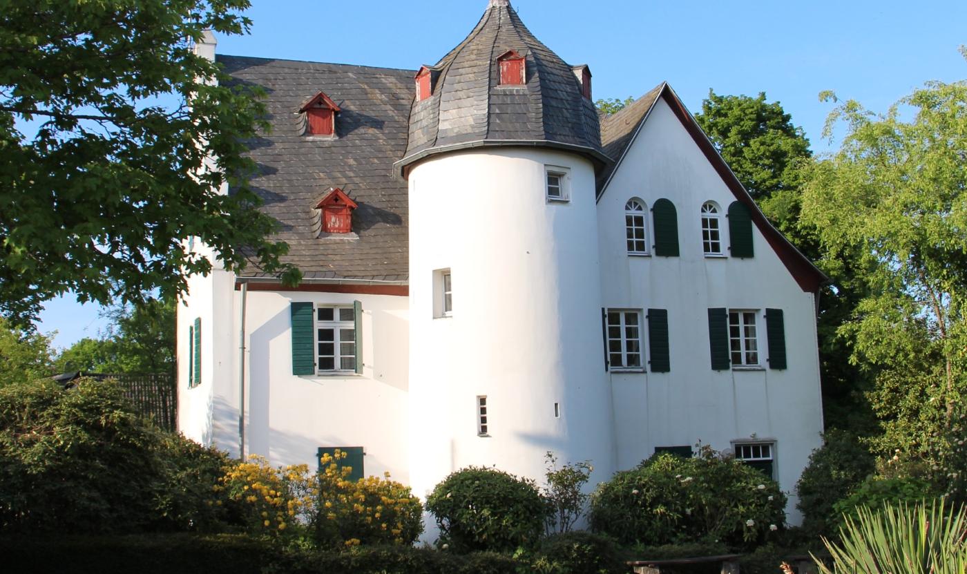 Friedenberger Hof mit Bäumen und blauem Himmel